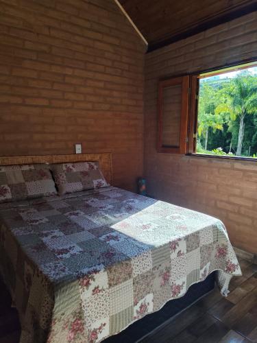 a bedroom with a bed with a quilt on it at Chalés Beira Rio in Santo Antônio do Pinhal