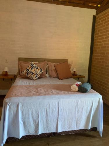 a bedroom with a bed with a white bedspread and pillows at chalés Roma in Santo Antônio do Pinhal