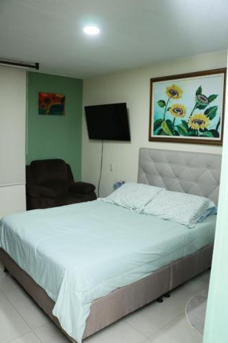 a bedroom with a bed and a chair and a television at Spazio83 in Puerto Colombia
