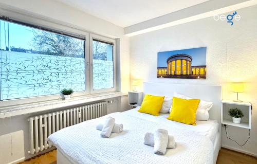 a bedroom with a bed with yellow pillows and a window at BEGE APARTMENTS CitySleep in Aachen