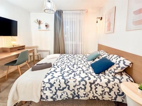 a bedroom with a bed with blue pillows and a desk at Le Cosy Saint-Cyr in Saint-Cyr-lʼÉcole
