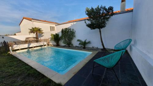 a swimming pool in a yard with two chairs at La Villa Estran in Saint-Gilles-Croix-de-Vie