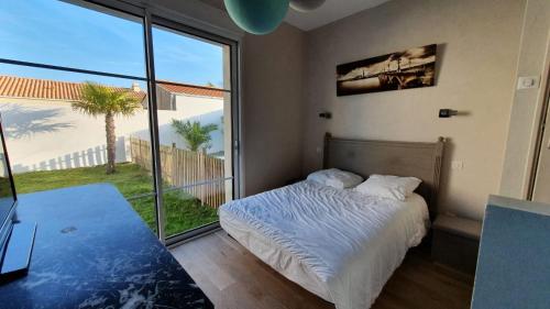 a bedroom with a bed and a large window at La Villa Estran in Saint-Gilles-Croix-de-Vie