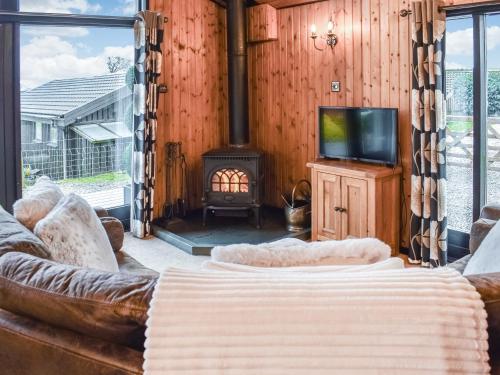 a living room with a couch and a tv and a fireplace at Glendowlin Lodge Retreat in Tirril