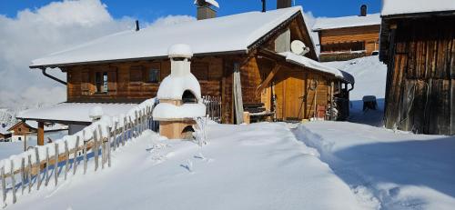 a fence covered in snow in front of a cabin at Alpenchalet Garfrescha in Sankt Gallenkirch