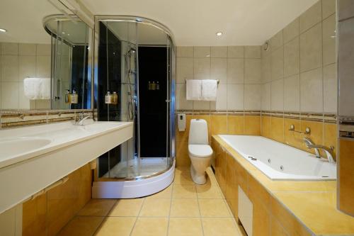 a bathroom with a tub and a toilet and a sink at Bergstadens Hotel & Spa in Røros