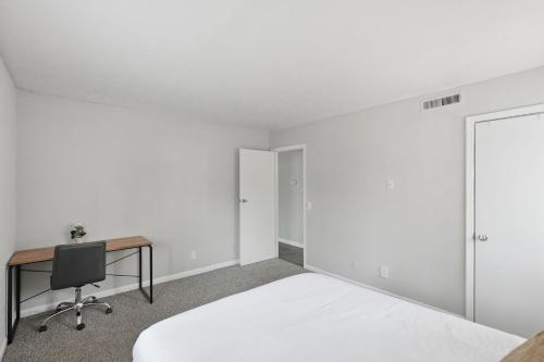 a white bedroom with a desk and a bed at Cozy Downtown Stone Mountain Apartment in Stone Mountain