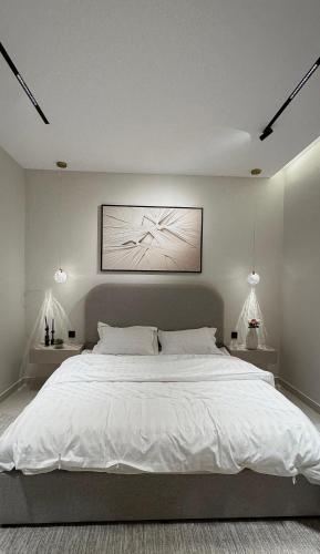 a bedroom with a large white bed with two lamps at ZA apartment in Al Ahsa