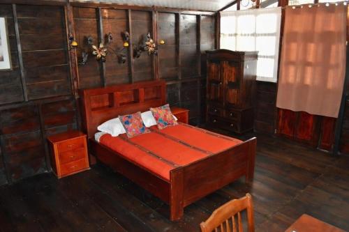 a bedroom with a bed in a room with wooden walls at El Refugio - Hospedaje y Eventos in San Lucas Sacatepéquez