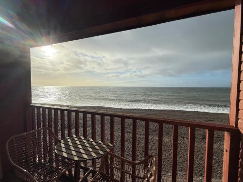 a balcony with a table and a view of the ocean at Branscombe Chalet on the Beach in Branscombe