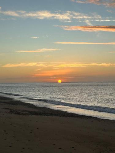 a sunset on the beach with the sun in the distance at Branscombe Chalet on the Beach in Branscombe