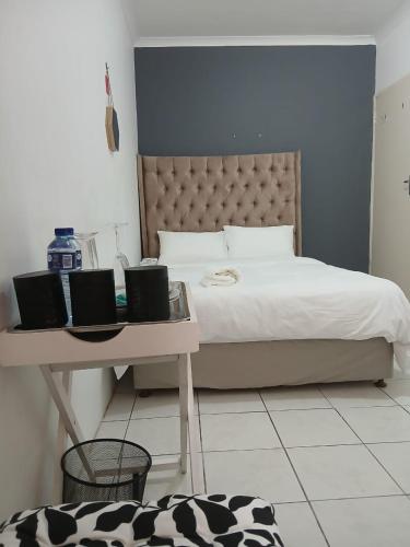 a bedroom with a bed with a table and a desk at DigiStay in Simonʼs Town