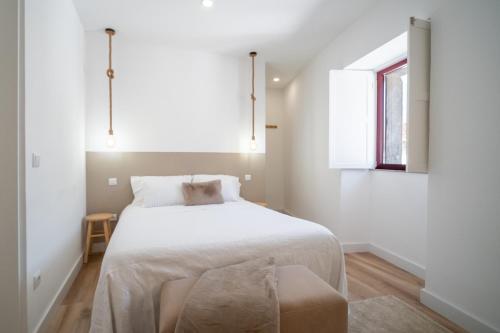 a white bedroom with a bed and a window at Portas da Villa in Miranda do Douro