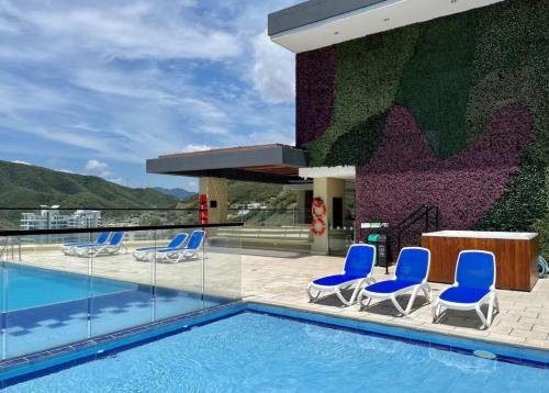 a pool with chairs and a table and a building at Nuevo SMART-HOME de Lujo a Playa Rodadero con Piscina Panorámica in Gaira