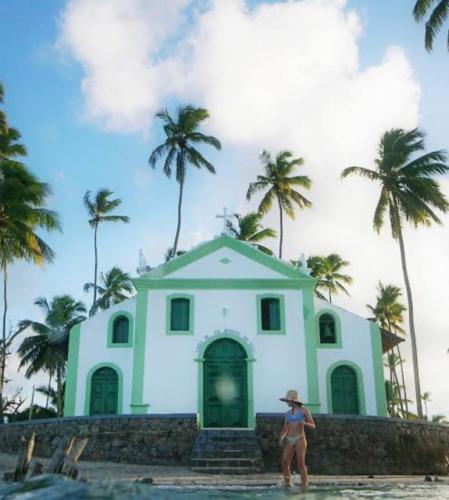 a woman standing in front of a building on the beach at Flat casa de madeira in São José da Coroa Grande
