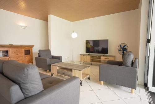 a living room with couches and a tv and a table at 3BR Beachfront Villa Steps from the Lagoon in Paopao