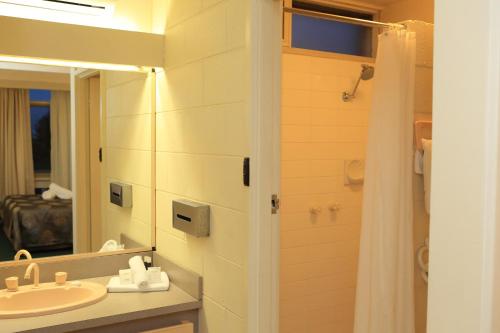 a bathroom with a sink and a mirror and a shower at Ocean Views Motel Lakes Entrance in Lakes Entrance