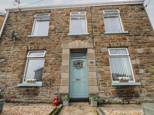 a brick house with a blue door and windows at Brynawel in Burry Port