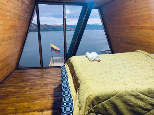 a bedroom with a bed with a view of the water at Lago de Tota GALAMPLAY lodge in Tota