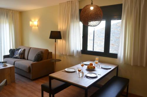 a living room with a table and a couch at Pierre & Vacances Andorra Sunari Peretol in Bordes d´Envalira