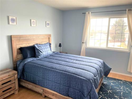 a bedroom with a blue bed and a window at Spacious Duplex in Camrose