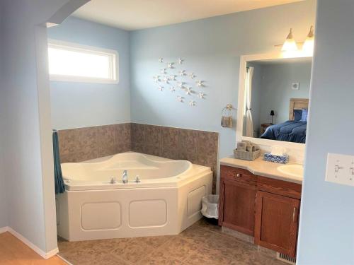 a bathroom with a tub and a sink and a mirror at Spacious Duplex in Camrose