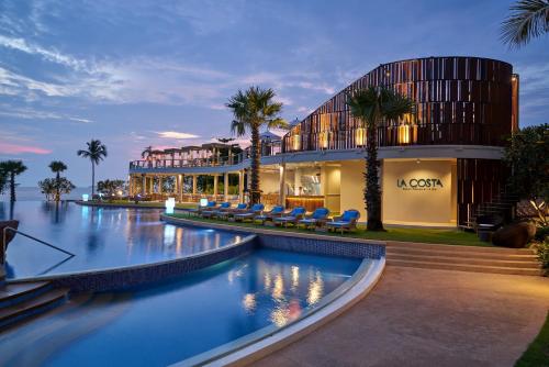 a hotel with a swimming pool in front of a building at Mövenpick Siam Hotel Na Jomtien Pattaya in Na Jomtien