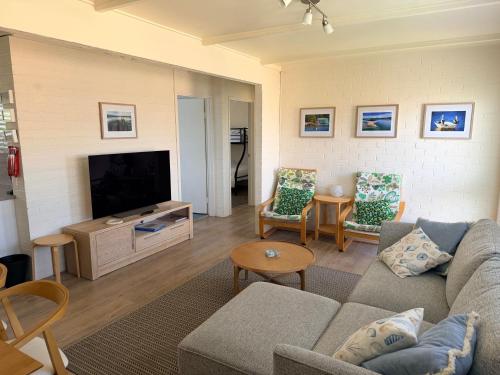 a living room with a couch and a tv at Seaspray in Merimbula