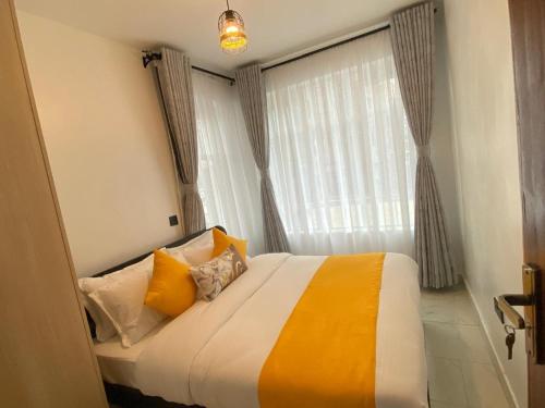a bedroom with a bed with yellow pillows and a window at Urbanza Haven Nakuru in Nakuru