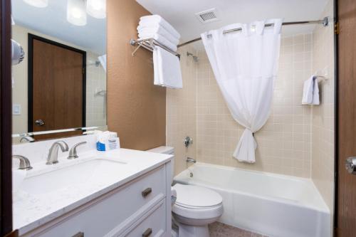 a bathroom with a sink and a toilet and a tub at MCM Elegante Suites Abilene in Abilene
