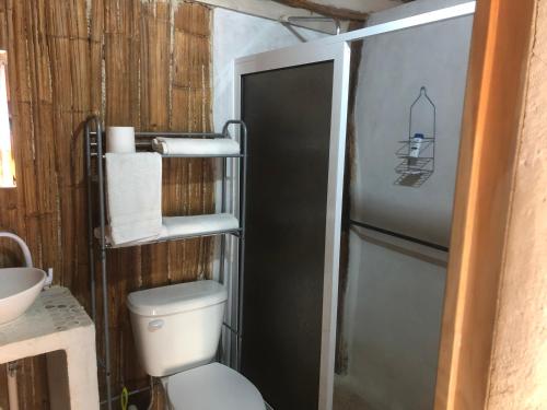 a bathroom with a toilet and a refrigerator at Cabañas Cinco Elementos in Celestún