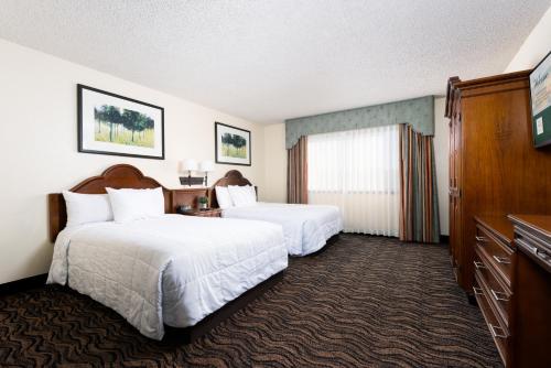 a hotel room with two beds and a television at MCM Elegante Suites Abilene in Abilene
