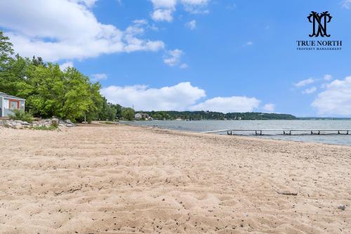 a sandy beach with a house and the water at Beautiful Lake View Studio Condo at The Shores in Traverse City
