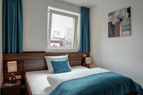a bedroom with a bed and a window with blue curtains at North-Hotel in Hamburg
