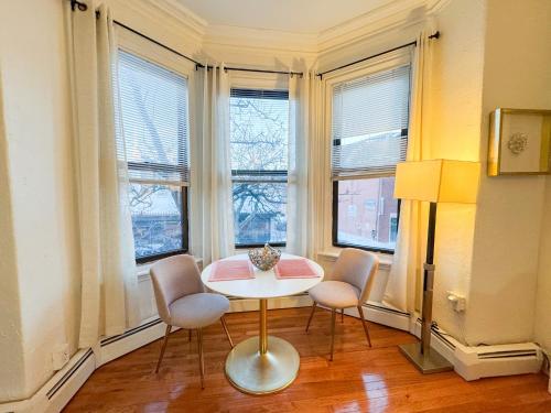 a table and chairs in a room with windows at Cozy 1Bed, 1Bath in Brookline, MBTA in Brookline