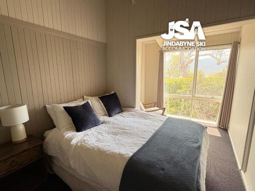 a bedroom with a bed with blue pillows and a window at Kalkite Cottage in Kalkite