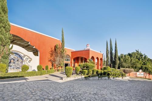 an orange building with trees and bushes in front of it at Fiesta Americana Hacienda Ixtapan de La Sal in Ixtapan de la Sal