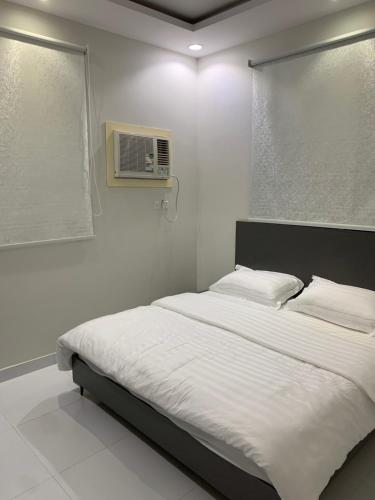 a white bedroom with a bed with a microwave at City residence in Medina
