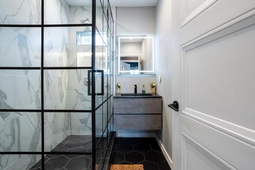 a glass shower door in a bathroom with a sink at Newly Renovated Bungalow w Free Parking 4min from SoFi, 8min from Airport in Los Angeles