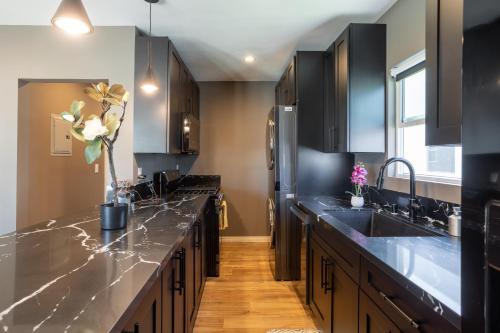 a kitchen with black cabinets and marble counter tops at Newly Renovated Bungalow w Free Parking 4min from SoFi, 8min from Airport in Los Angeles