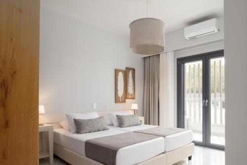 a white bedroom with a large bed and a window at Villa Kalliston - 4000m2 of Elevated Living in Rethymno