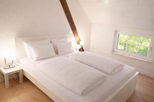 a white bed with white sheets and a window at Ostfrieschen Ferienwohnung & Spielscheune in Oldendorf