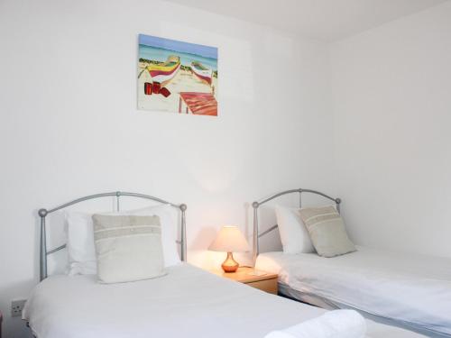 two beds in a bedroom with a picture on the wall at Gilly's Cottage in Kingsbridge