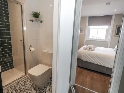 a bathroom with a shower and a toilet and a bed at Vista Mare 2 in Weymouth