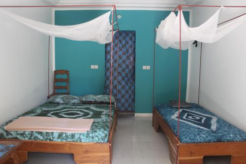 two beds in a room with blue walls at Campement Emanaye in Oussouye