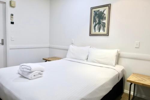 a bedroom with a white bed with towels on it at Park Avenue Hotel Motel in Rockhampton
