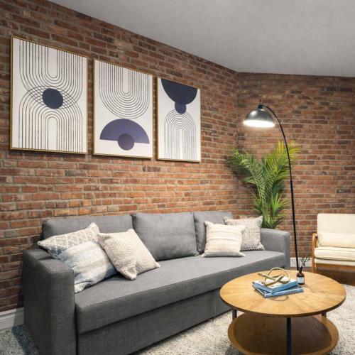 a living room with a couch and a brick wall at Modern Manhattan Haven Near Everything in New York