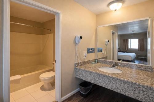 a bathroom with a sink and a toilet and a mirror at Scottish Fairway Inn in Monterey