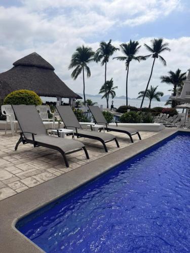 a group of chairs sitting next to a swimming pool at Depto familiar con vista al mar en Playasol Manzanillo in Manzanillo