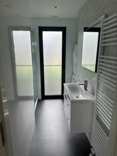 a white bathroom with a sink and a mirror at Bad Hoophuizen Chalet L-Cube 6 Nr Eik 19 in Hulshorst